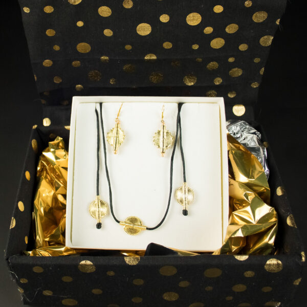 Coffret cadeau Jojo Création Poids Akan Soleil : parure de bijoux dorés circulaires dans une boîte noire à pois dorés.